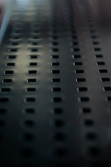 textured black surface with many small squares in a row with white reflection