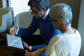 Optometrist discussing over graphic tablet with patient