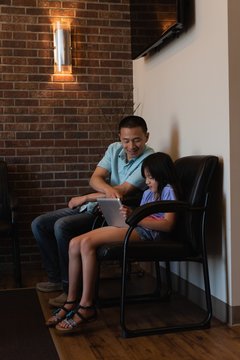 Father and daughter using digital tablet in dental clinic