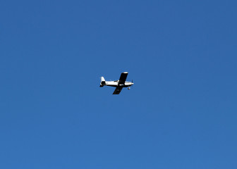 white airplane flies in the blue sky over the river and rolls people.
