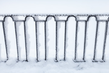 Forged black fence covered with snow,