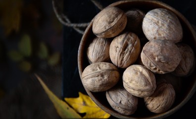 Walnuts on a black stand on the background of autumn leaves.