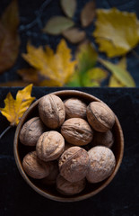 Walnuts on a black stand on the background of autumn leaves.