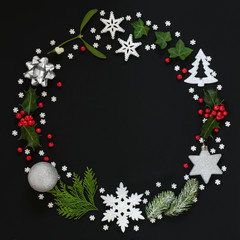 Abstract Christmas wreath garland with winter flora and bauble decorations on black background. Top...