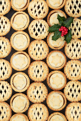 Delicious freshly baked Christmas home made mince pies with holly berry leaf sprig forming a background. Top view. 