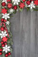 Christmas background border with bauble decorations, spruce fir and mistletoe isolated on rustic grey wood. Festive theme.
