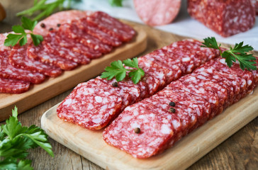 Sliced salami with parsley on a wooden cutting board