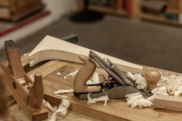 Eco friendly woodworker's shop. Details and focus on the texture of the material, saw dust, and planers or chisels, while making legs for a designer coffee table. Mastering wood with peacefullness.