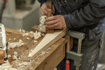 Eco friendly woodworker's shop. Details and focus on the texture of the material, saw dust, and planers or chisels, while making legs for a designer coffee table. Mastering wood with peacefullness.