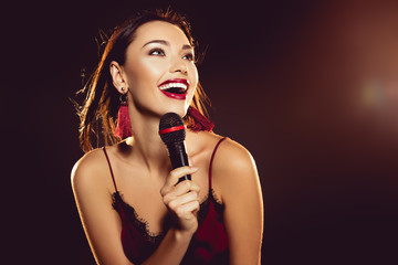 portrait of happy young woman with microphone in hand singing karaoke