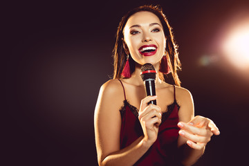 portrait of excited beautiful woman with microphone in hand singing karaoke