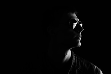 Young man's black and white portrait. Close-up young man in a black leather jacket and sunglasses