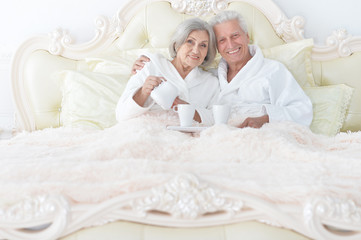 Obraz na płótnie Canvas Portrait of senior couple in bed with tea