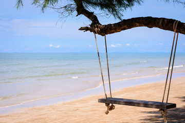 Wooden swing hanging from a tree on the beach. A tropical beach in southern part of Thailand in sunny day.