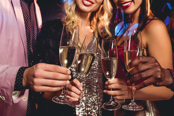 cropped view of glamorous friends clinking with champagne glasses