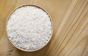 Raw, parboiled rice in a wooden bowl. Rice dish on a wooden table, diet or healthy eating scene.