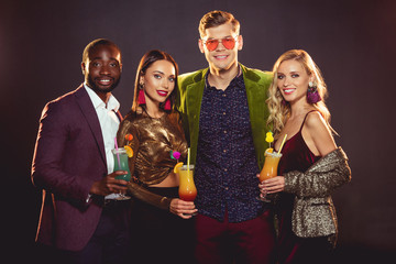 smiling glamorous multiethnic friends with alcohol cocktails on party