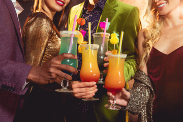 cropped view of friends holding alcohol cocktails on party