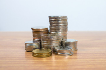 Stack of coins on an old wood table and white background.