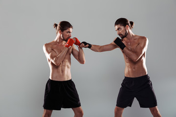 Portrait of a two serious muscular shirtless twin brothers