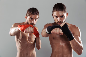Fototapeta na wymiar Portrait of a two serious muscular shirtless twin brothers