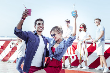 Nonstop party. Kind female person embracing her partner while having joyful mood