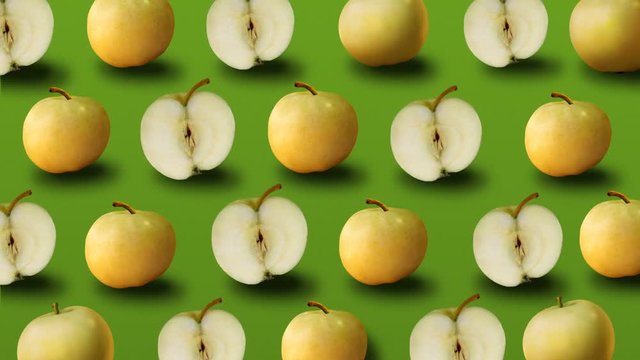 Colorful fruit pattern of fresh yellow apples on green background. 4k video.