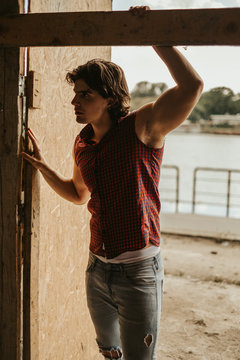 Handsome muscular man in sleeveless shirt standing in doorway
