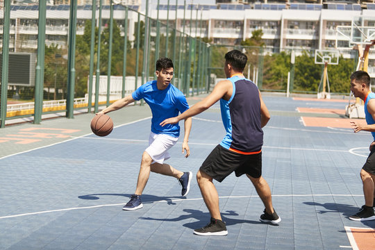 young asian adults playing basketball