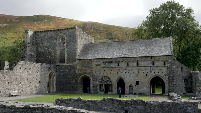 Distant unidentifiable tourists visit and take pictures of the ruins of the Valle Crucis Abbey in Denbighshire, Wales