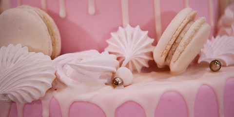 beautiful delicious birthday cake decorated with pink icing, meringues and marshmallows