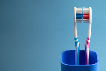 couple of toothbrushes in a plastic сup - obrazy, fototapety, plakaty