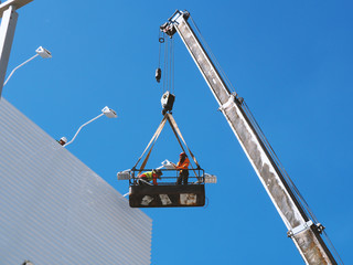 construction worker at construction site using lifting boom machinery