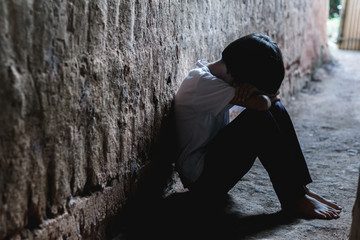 Helpless girl sitting on floor against old earth brick wall,children violence and abused concept,human trafficking concept