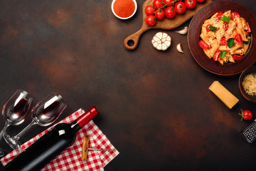Obraz na płótnie Canvas Pasta with cheese, cherry tomato sauce, wineglass and bottle wine, garlic, turmeric on rusty background
