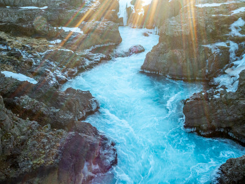 Water flow in nearby river near Hraunfossar waterfall with snow and ice in winter season, Iceland
