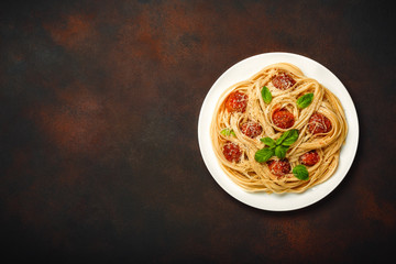 Spaghetti pasta with meatballs, cherry and tomato sauce on rusty background