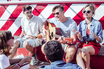 Join me. Cheerful blonde female keeping smile on her face while holding bottle with drink in left hand