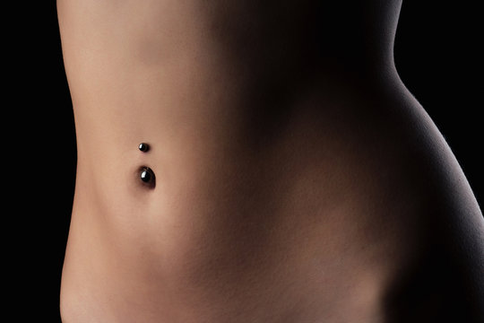 perfect female body Navel piercing erotic photoshoot on black background in studio shot
