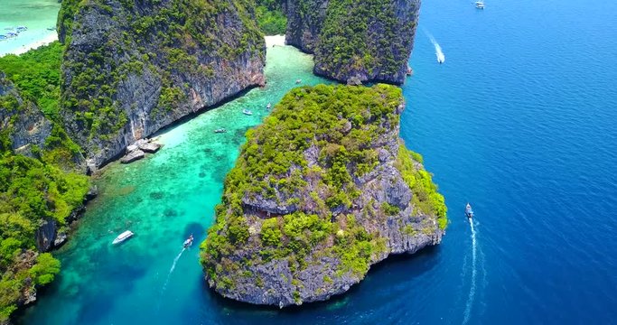 Aerial Overhead View of Lush Tropical Cove With Visible Coral Reef in Turquoise Water and Multiple Boats Moving Around Islands - Loh Samah Bay, Thailand