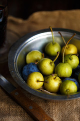 Wild pear and plums in a metal bowl