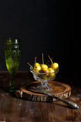 Wild pear in a glass bowl and a glass of homemade wine on a wooden dark background. Rustic concept