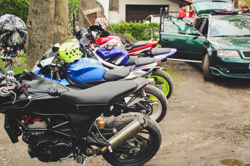 Sports motorcycles are near the house. The blue, red and black motobike. Hangover bikers