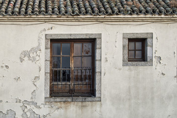 Obraz premium Fachada con dos ventanas/ Una vieja fachada de una casa rural con dos ventanas de distinto tamaño.