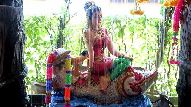 Phra Mae Thorani, goddess from Buddhist mythology, behind water of fountain.