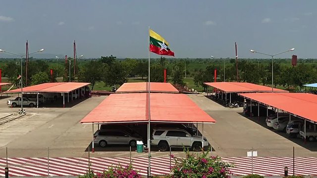 Myanmar's national flag flies above the parking lot at Mandalay Airport, Burma.The flag of Myanmar (Burma) flutters on parking zone, slow motion.