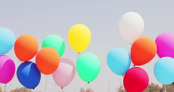 Sliding near multicolored balloons moving at wind on sky background