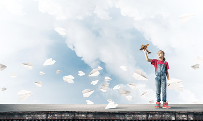 Concept of careless happy childhood with girl dreaming to become
