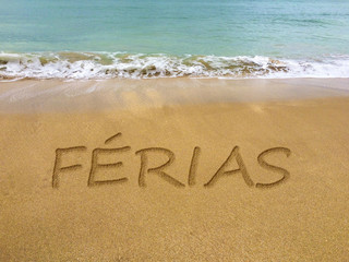 Vacation written in the sand on a beautiful Brazilian beach (translation portuguese: vacation).