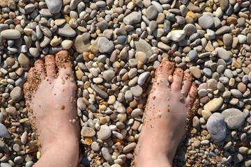 women's feet close-up on sea pebbles